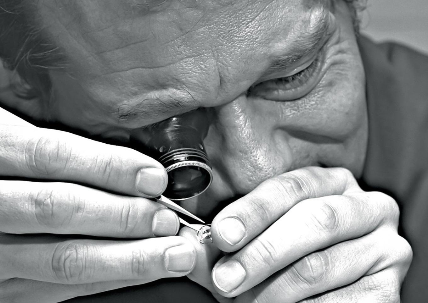 Watchmaker examining movement component with loupe
